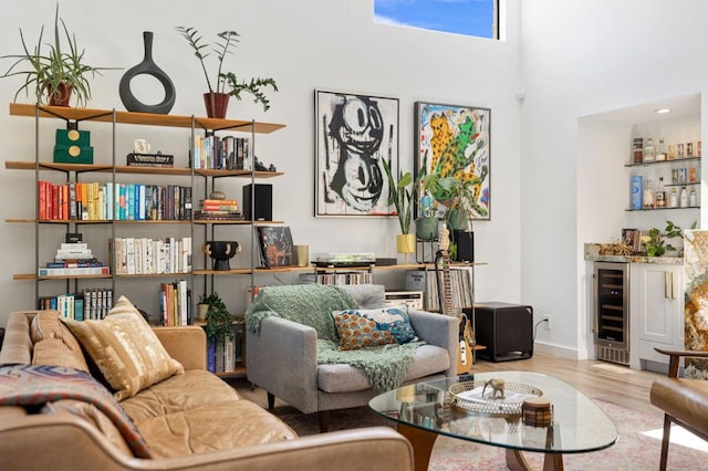 living room with beverage cooler, light wood-type flooring, and a high ceiling