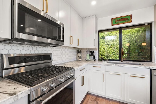 kitchen with light hardwood / wood-style floors, sink, stainless steel appliances, light stone countertops, and white cabinets