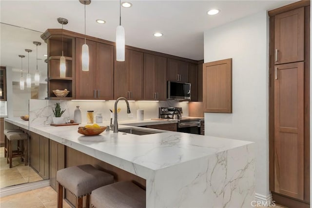 kitchen featuring kitchen peninsula, a kitchen bar, sink, hanging light fixtures, and stainless steel appliances