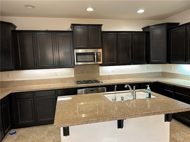 kitchen with sink, a kitchen island with sink, a kitchen bar, and stainless steel appliances