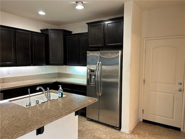 kitchen featuring stainless steel refrigerator with ice dispenser, sink, and stone counters