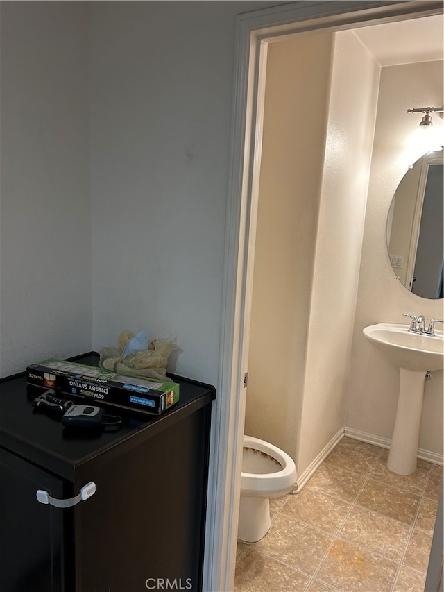 bathroom with toilet, sink, and tile patterned flooring