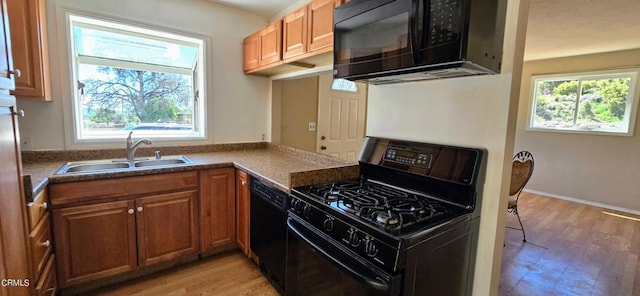 kitchen featuring a healthy amount of sunlight, sink, black appliances, and light hardwood / wood-style floors