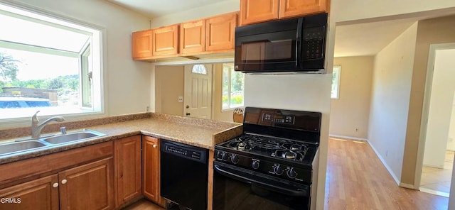 kitchen with black appliances, plenty of natural light, light hardwood / wood-style floors, and sink