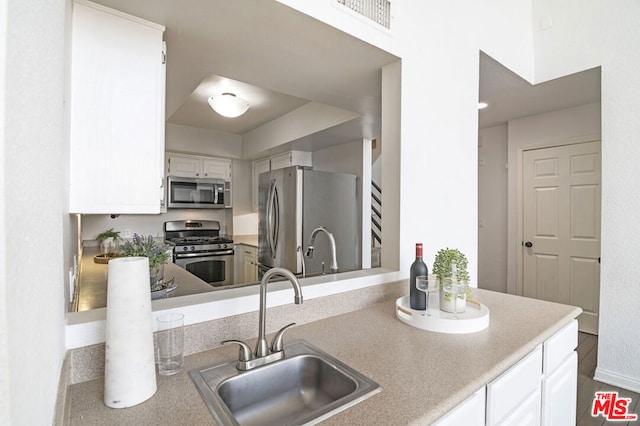 kitchen with appliances with stainless steel finishes, white cabinetry, and sink