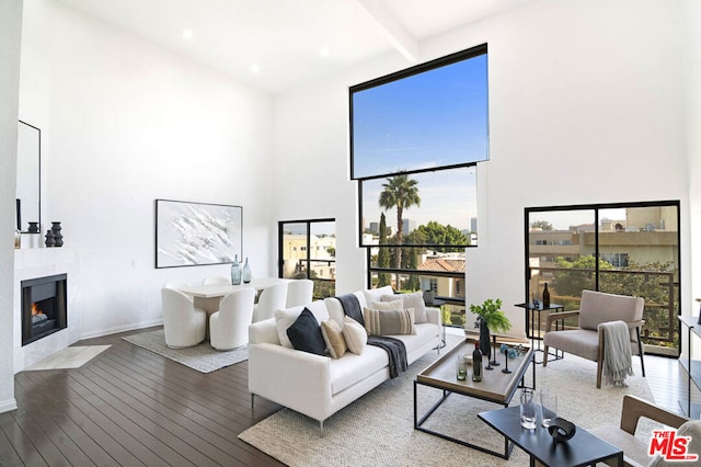 living room featuring beam ceiling, a tile fireplace, plenty of natural light, and hardwood / wood-style floors