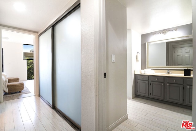 hallway featuring floor to ceiling windows, sink, and light hardwood / wood-style flooring