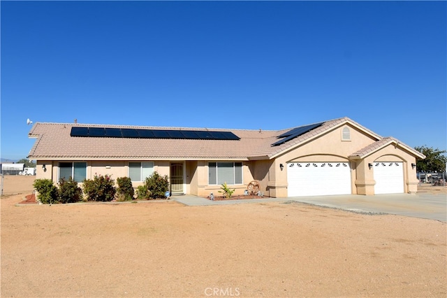 ranch-style home featuring a garage and solar panels