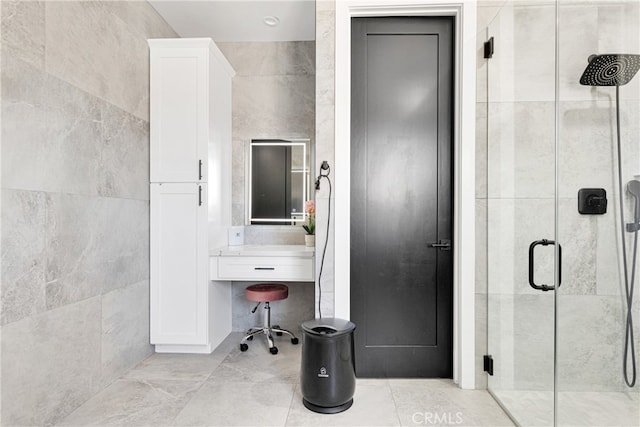 bathroom with tile walls, vanity, and a shower with shower door