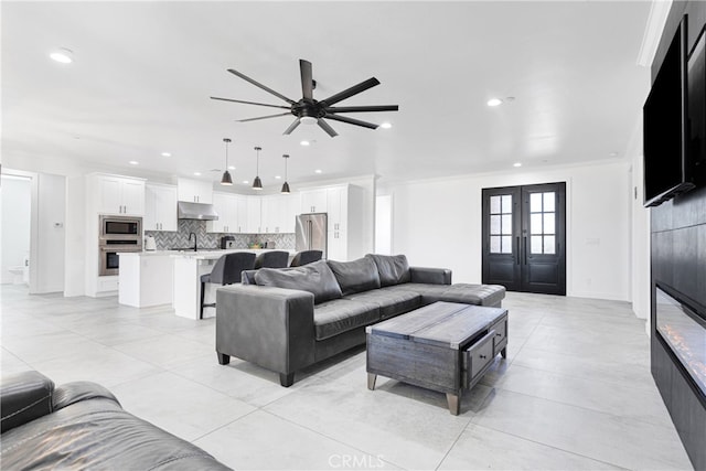 living room featuring ceiling fan, sink, french doors, ornamental molding, and light tile patterned floors