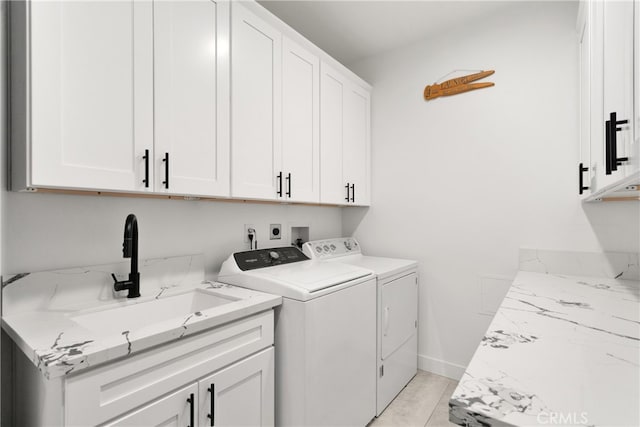 laundry area with light tile patterned floors, cabinets, sink, and washing machine and clothes dryer