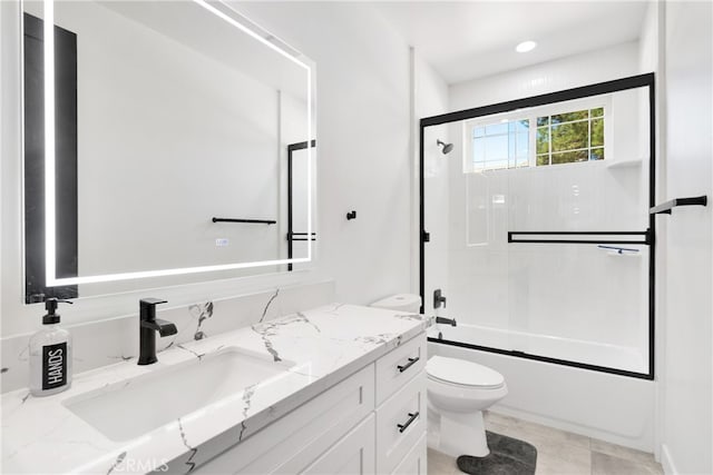 full bathroom featuring combined bath / shower with glass door, tile patterned floors, vanity, and toilet