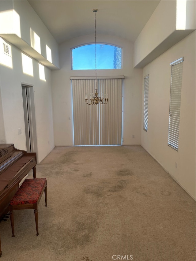 interior space featuring high vaulted ceiling, carpet flooring, and an inviting chandelier