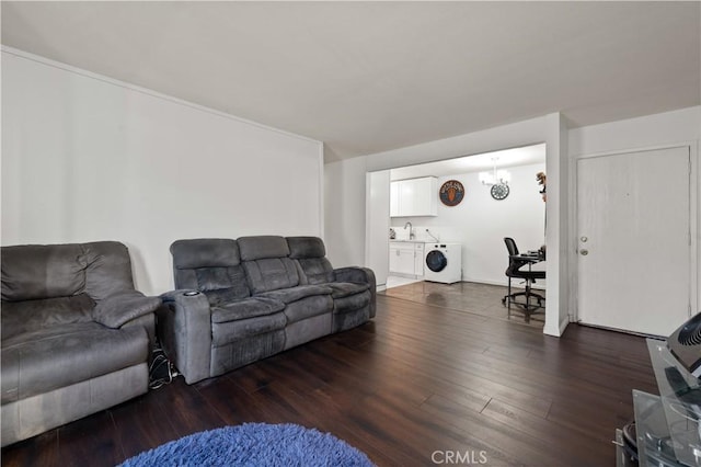 living room with sink, dark hardwood / wood-style floors, a chandelier, and washing machine and dryer