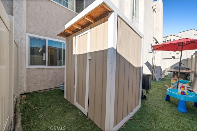 view of side of home featuring a lawn and a storage unit