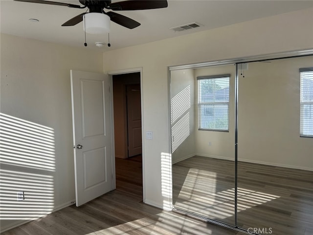 unfurnished bedroom with ceiling fan, dark hardwood / wood-style flooring, and a closet