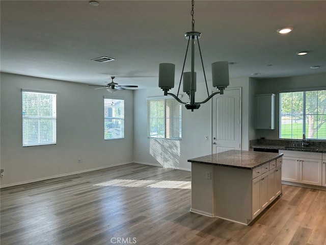 kitchen with white cabinets, plenty of natural light, hanging light fixtures, and a kitchen island