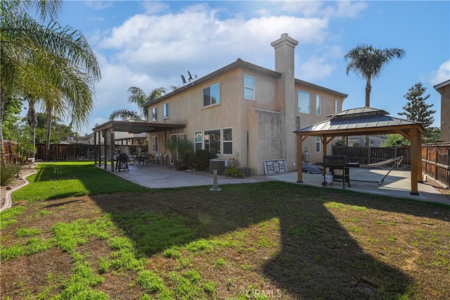 rear view of property with a gazebo, a patio, and a lawn