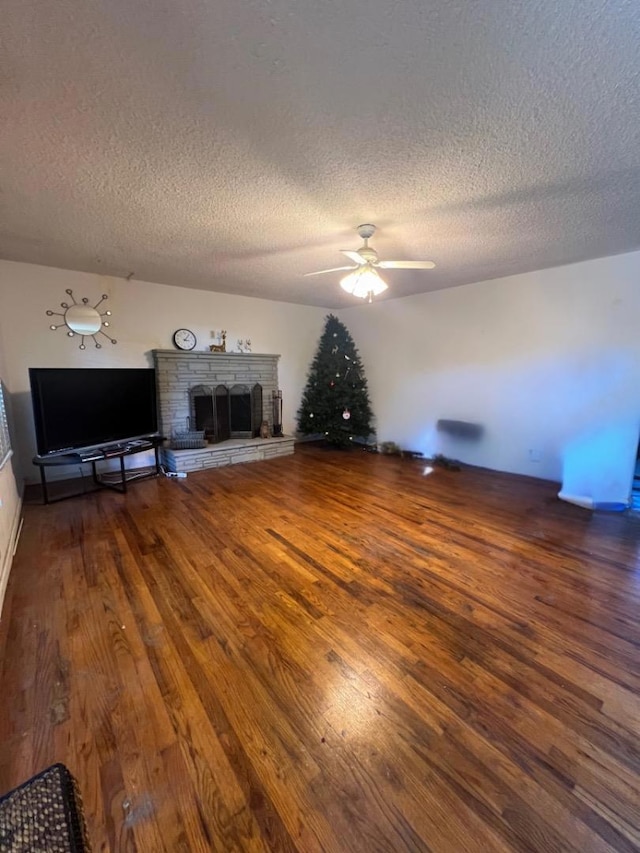 unfurnished living room featuring a textured ceiling, ceiling fan, a fireplace, and wood-type flooring