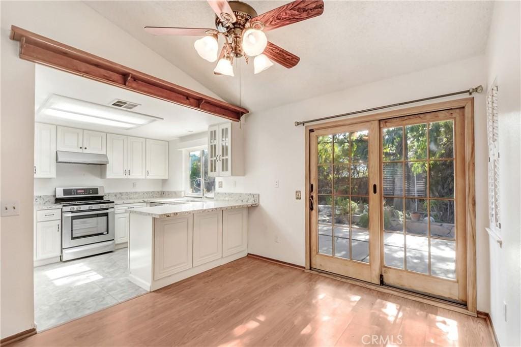 kitchen featuring white cabinetry, lofted ceiling, stainless steel gas range, and kitchen peninsula