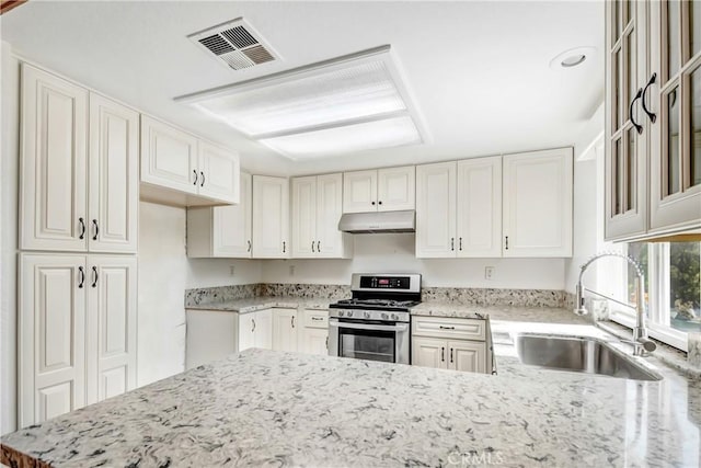 kitchen featuring sink, gas range, light stone countertops, and white cabinets