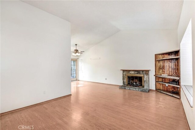 unfurnished living room featuring hardwood / wood-style flooring, ceiling fan, lofted ceiling, and a stone fireplace