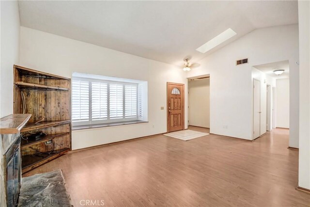 unfurnished living room with hardwood / wood-style flooring and lofted ceiling with skylight