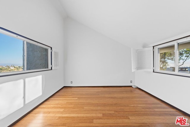 spare room featuring light hardwood / wood-style flooring and vaulted ceiling