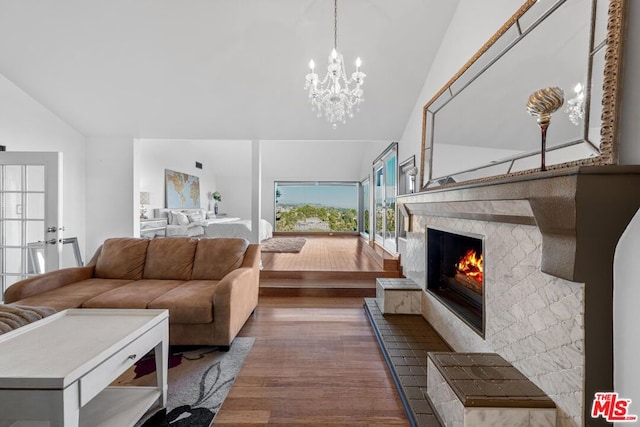 living room featuring a notable chandelier, a fireplace, dark hardwood / wood-style floors, and vaulted ceiling