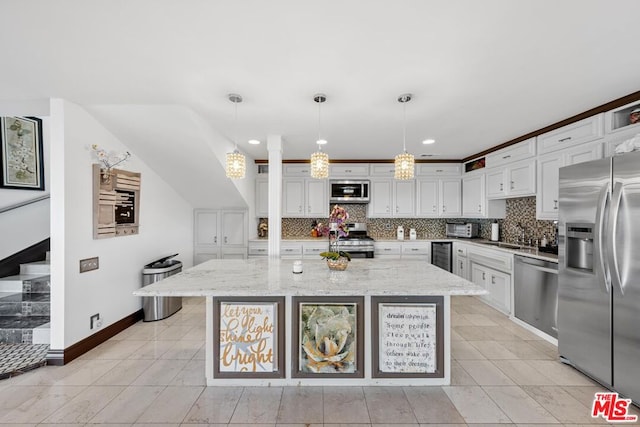 kitchen featuring light stone counters, hanging light fixtures, a kitchen island, white cabinetry, and appliances with stainless steel finishes