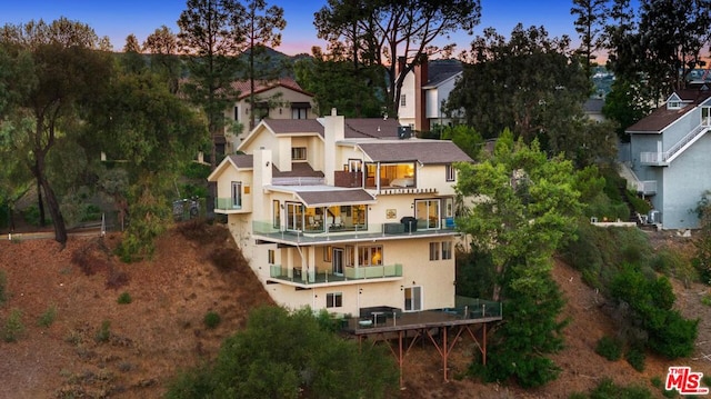 back house at dusk with a balcony