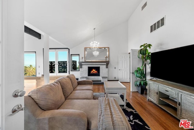 living room featuring a chandelier, high vaulted ceiling, and hardwood / wood-style flooring