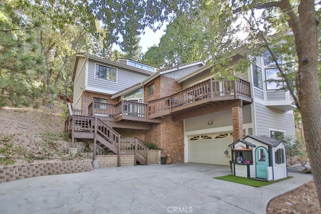 rear view of property with a garage, stairway, concrete driveway, and brick siding