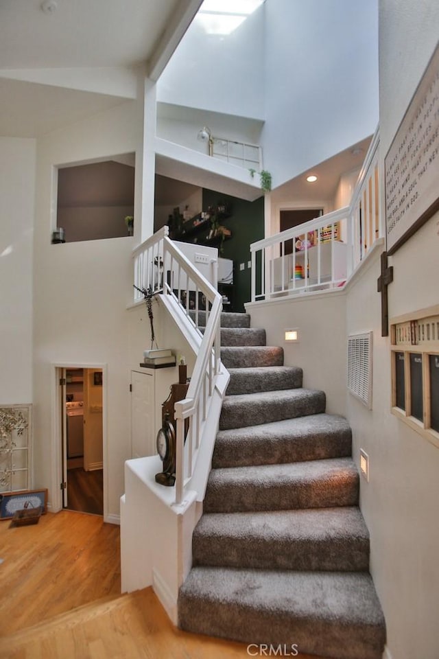 stairs featuring a high ceiling and hardwood / wood-style floors