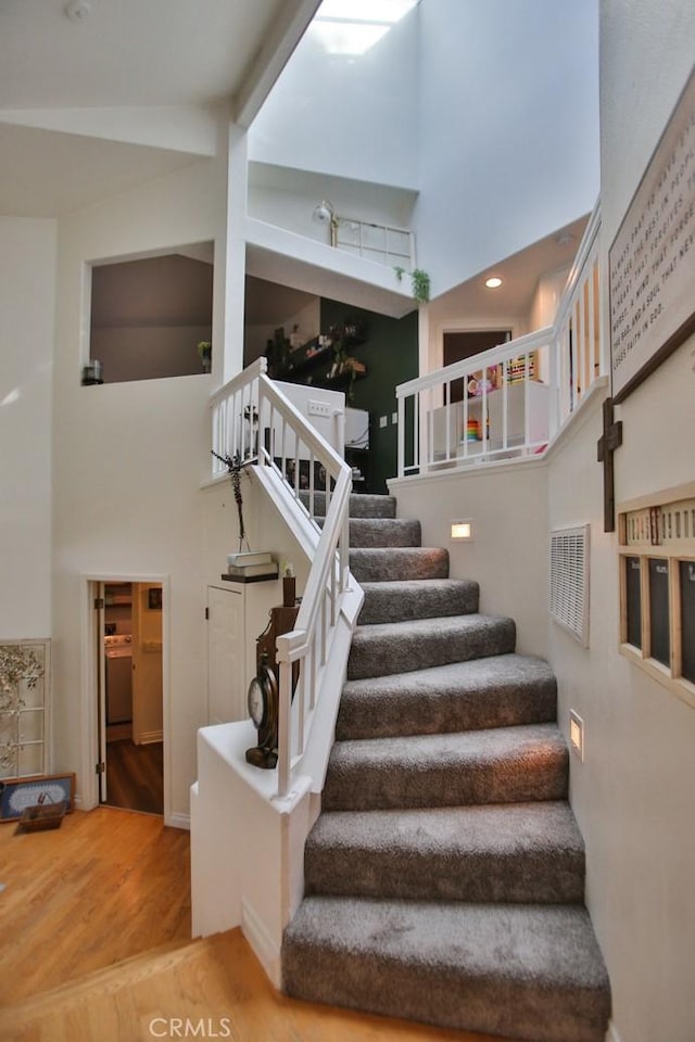 stairs featuring a towering ceiling, visible vents, and wood finished floors