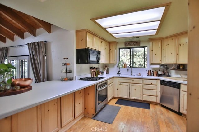 kitchen with light brown cabinetry, sink, stainless steel appliances, beam ceiling, and light hardwood / wood-style floors