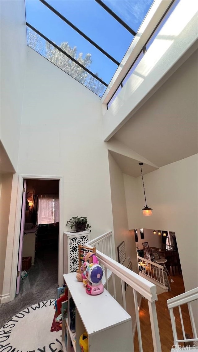 corridor with a skylight, a high ceiling, a wealth of natural light, and an upstairs landing