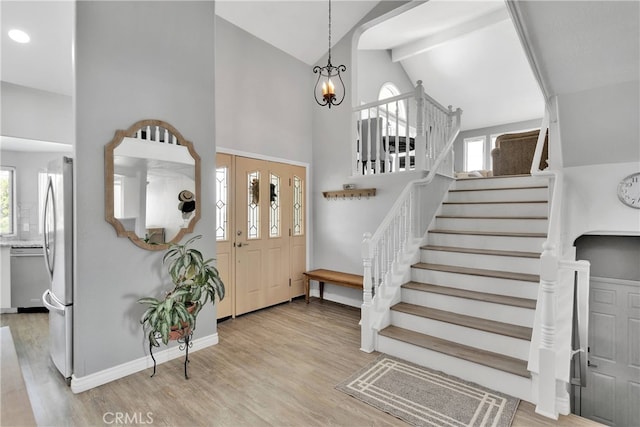 foyer entrance featuring high vaulted ceiling, beamed ceiling, and light hardwood / wood-style flooring