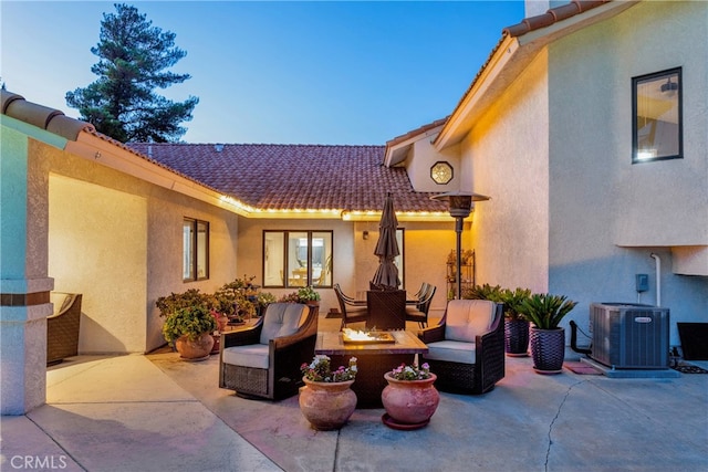 patio terrace at dusk with outdoor lounge area and central AC unit