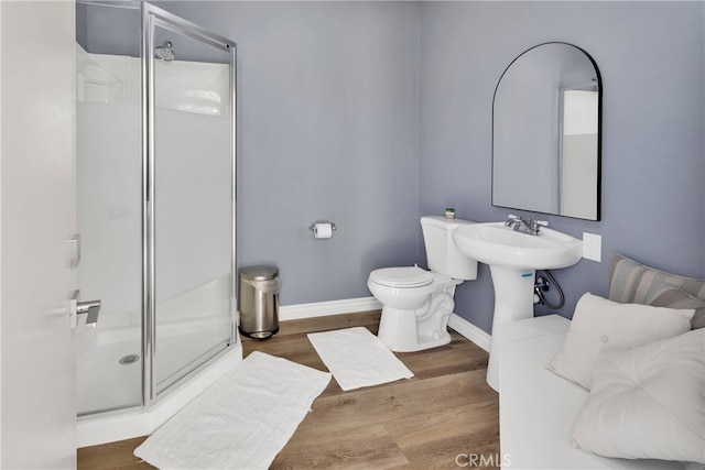 bathroom featuring wood-type flooring, a shower with door, and toilet