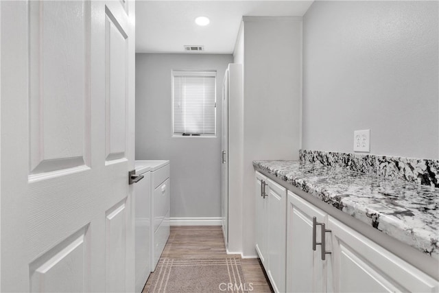 interior space with hardwood / wood-style flooring, washing machine and clothes dryer, and vanity