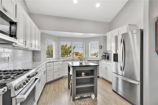 kitchen with backsplash, appliances with stainless steel finishes, a kitchen island, and white cabinetry