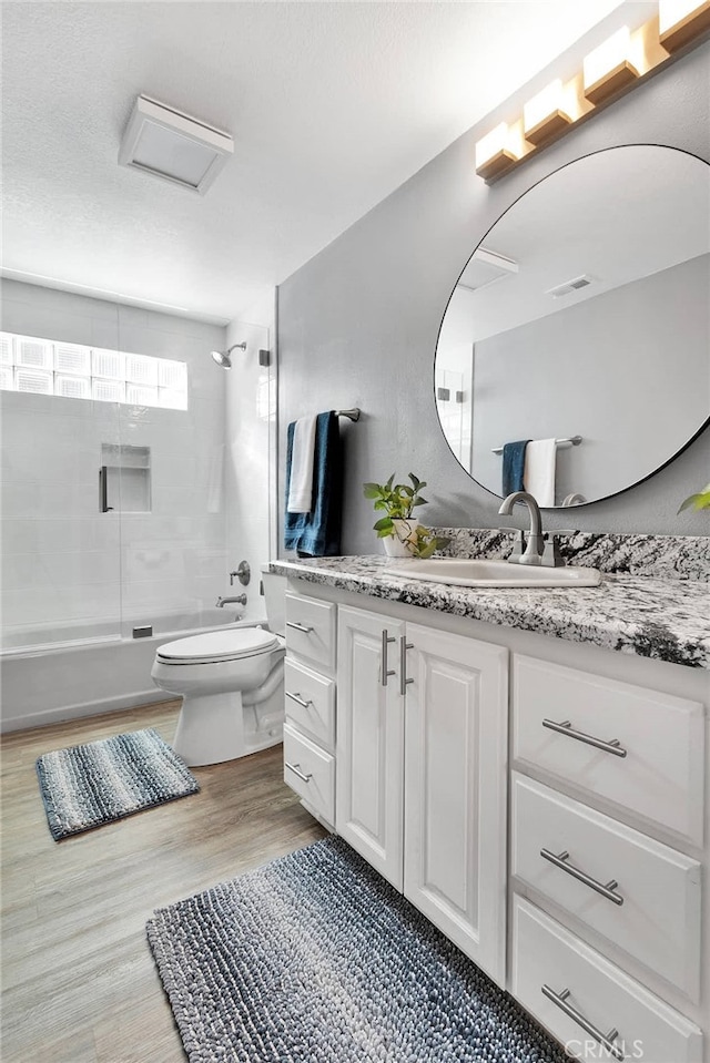 full bathroom with vanity, tiled shower / bath combo, toilet, and hardwood / wood-style flooring