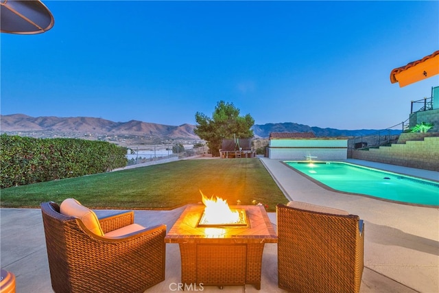 view of pool featuring a yard, a patio, a fire pit, and a mountain view