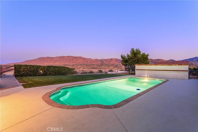 pool at dusk with a patio area and a mountain view