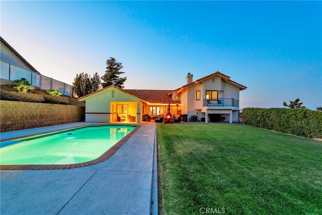 pool at dusk with a lawn and a patio area