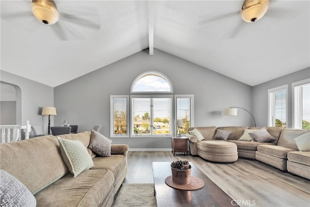 living room with ceiling fan, a wealth of natural light, light hardwood / wood-style floors, and vaulted ceiling with beams