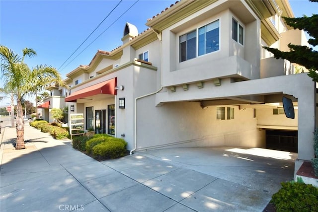 exterior space with a tile roof, driveway, and stucco siding