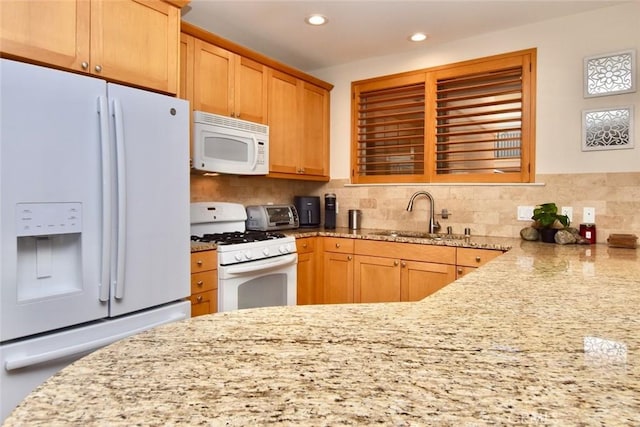 kitchen featuring a sink, light stone counters, backsplash, recessed lighting, and white appliances