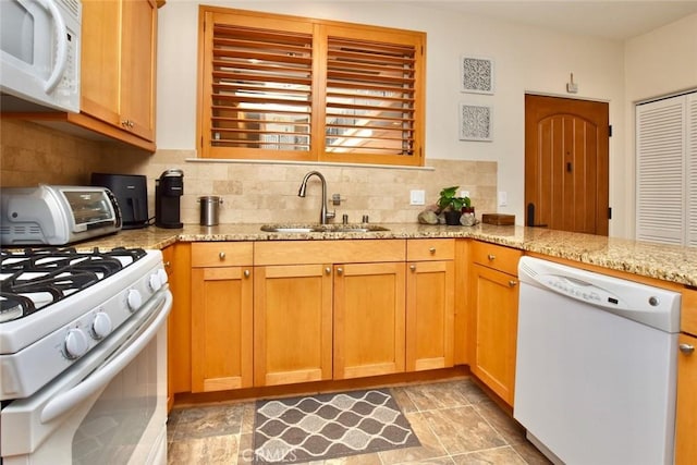 kitchen featuring a sink, white appliances, a toaster, decorative backsplash, and light stone countertops